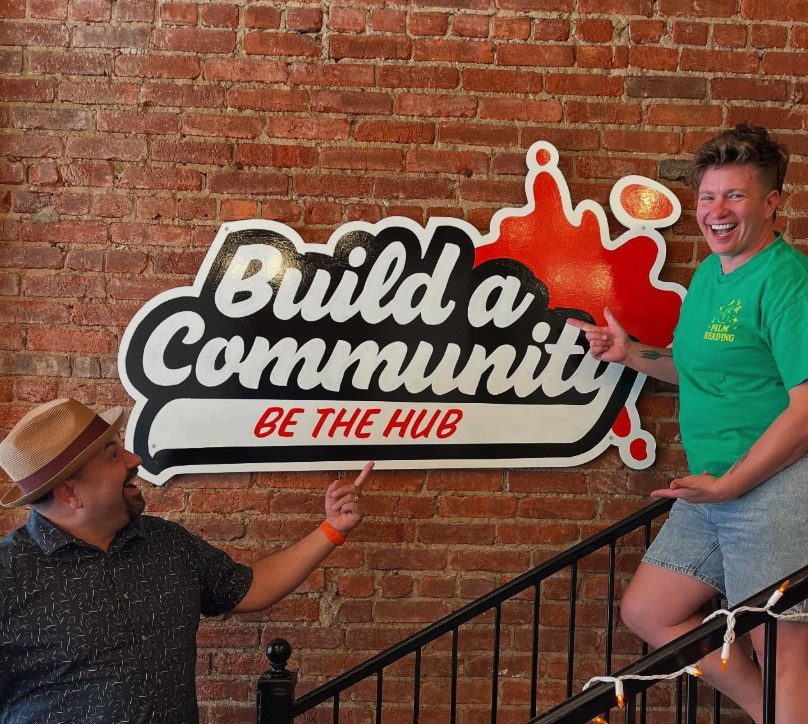Build a Community Be The Hub painted sign on brick wall